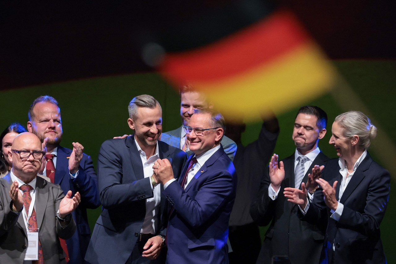 AfD politicians celebrating beneath a German flag in Saxony-Anhalt